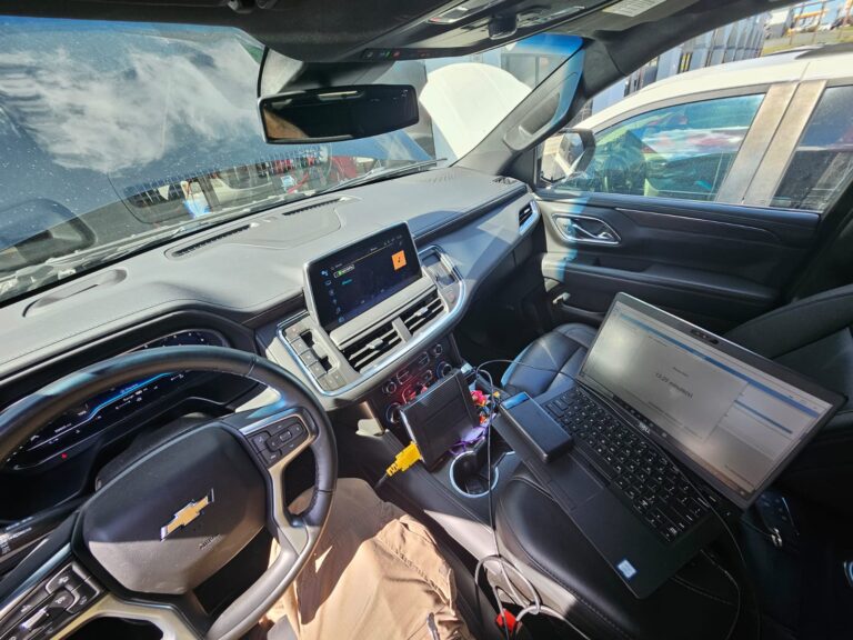 Automotive locksmith programming a car key inside a Chevrolet using advanced diagnostic tools and software