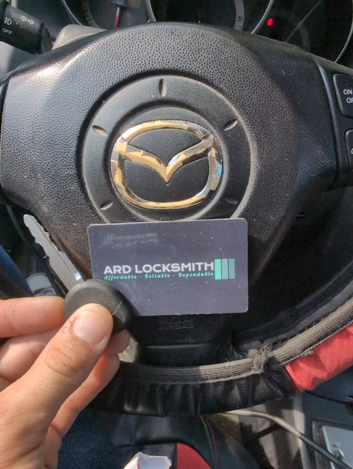 Completed Mazda 3 replacement key documented inside the vehicle with an ARD Locksmith card