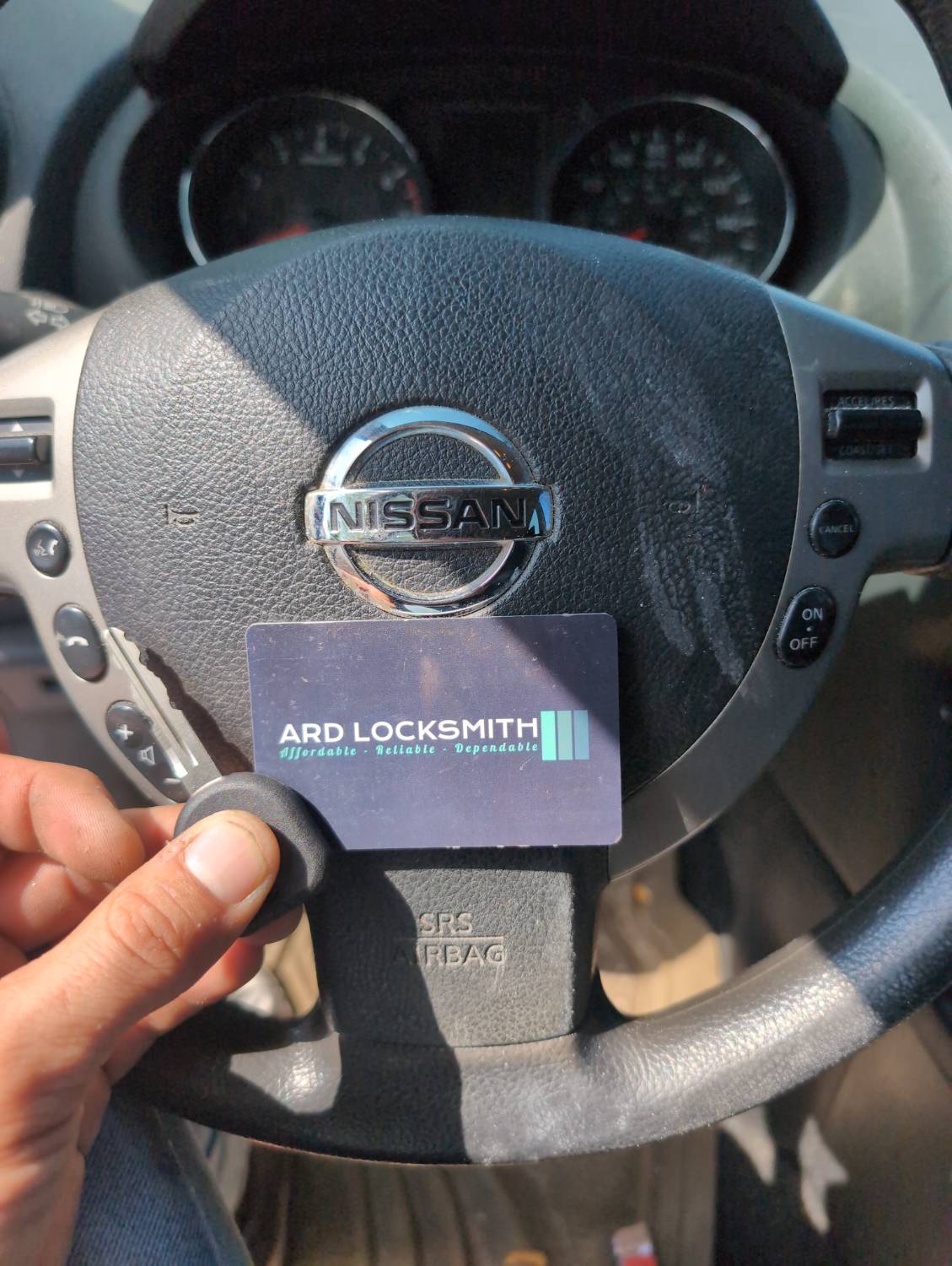 Completed Nissan Rogue replacement key documented inside the vehicle with an ARD Locksmith card