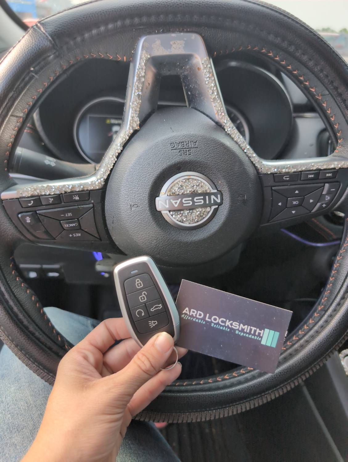 Completed Nissan Versa smart key documented inside the vehicle with an ARD Locksmith card