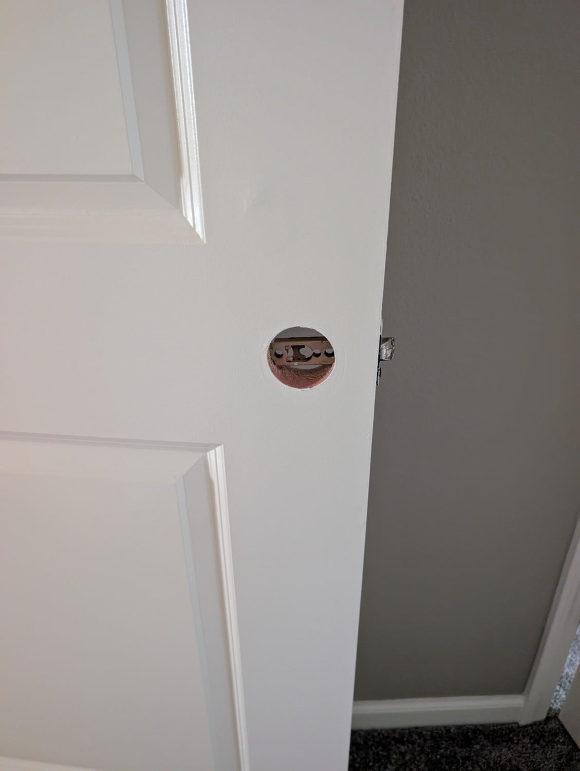 White interior door with the doorknob removed during a residential hardware replacement job.